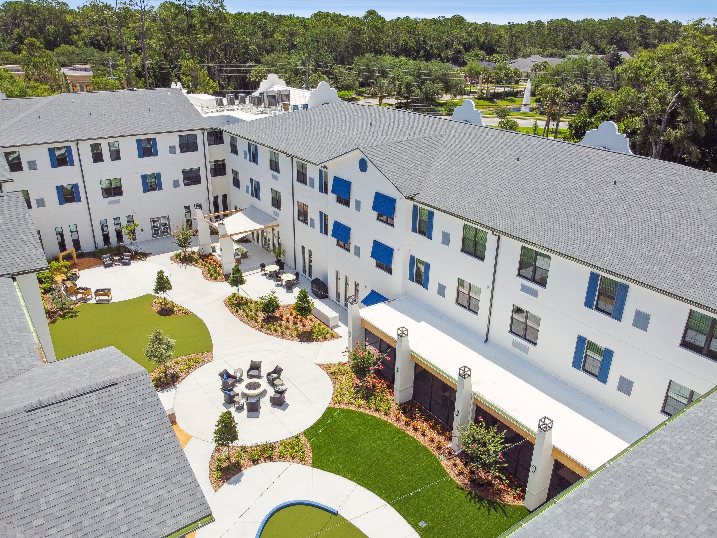 Aerial view of a senior living community courtyard furnished with contract‑grade outdoor seating, dining tables, and landscaped gathering areas.