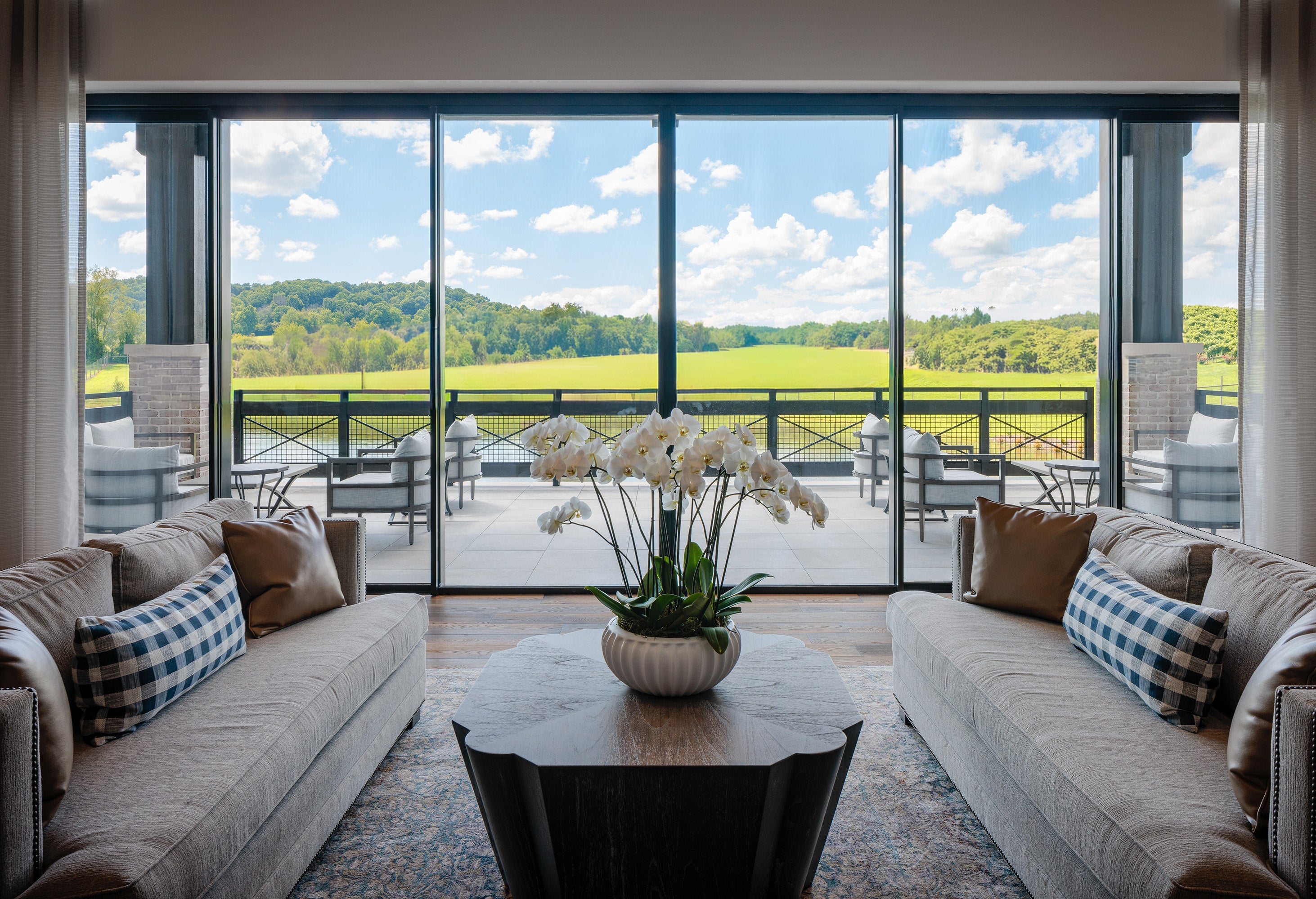 Modern living room with a view of a green landscape through large windows.
