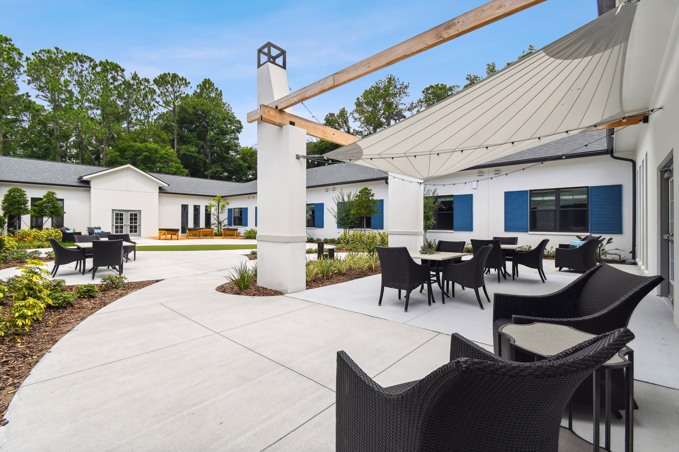 Outdoor seating area with tables and chairs in front of a building with blue shutters.