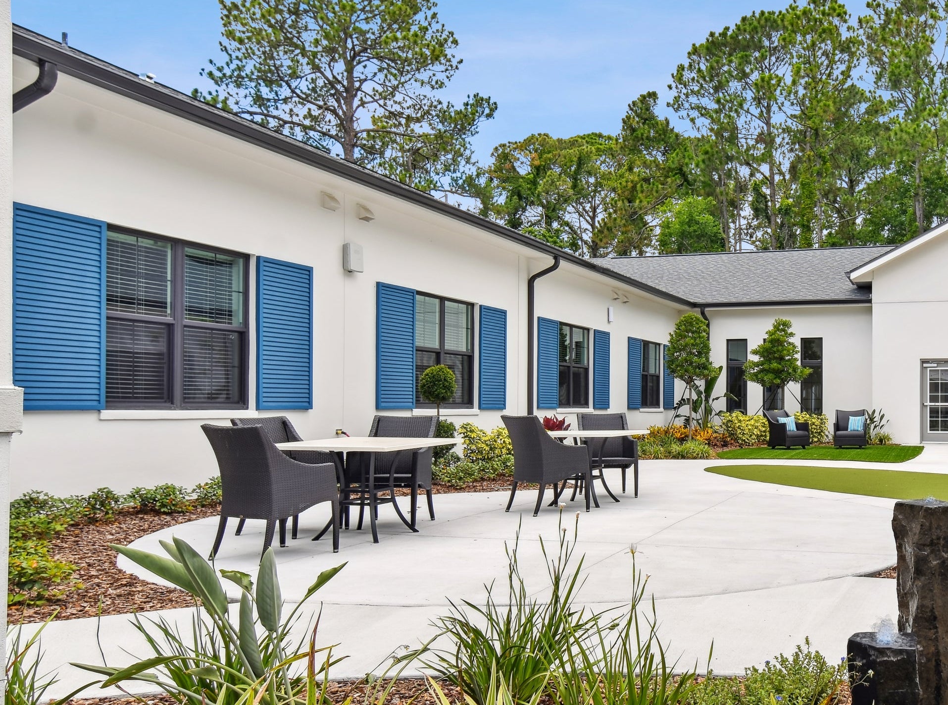 Outdoor area with patio furniture, trees, and a building in the background