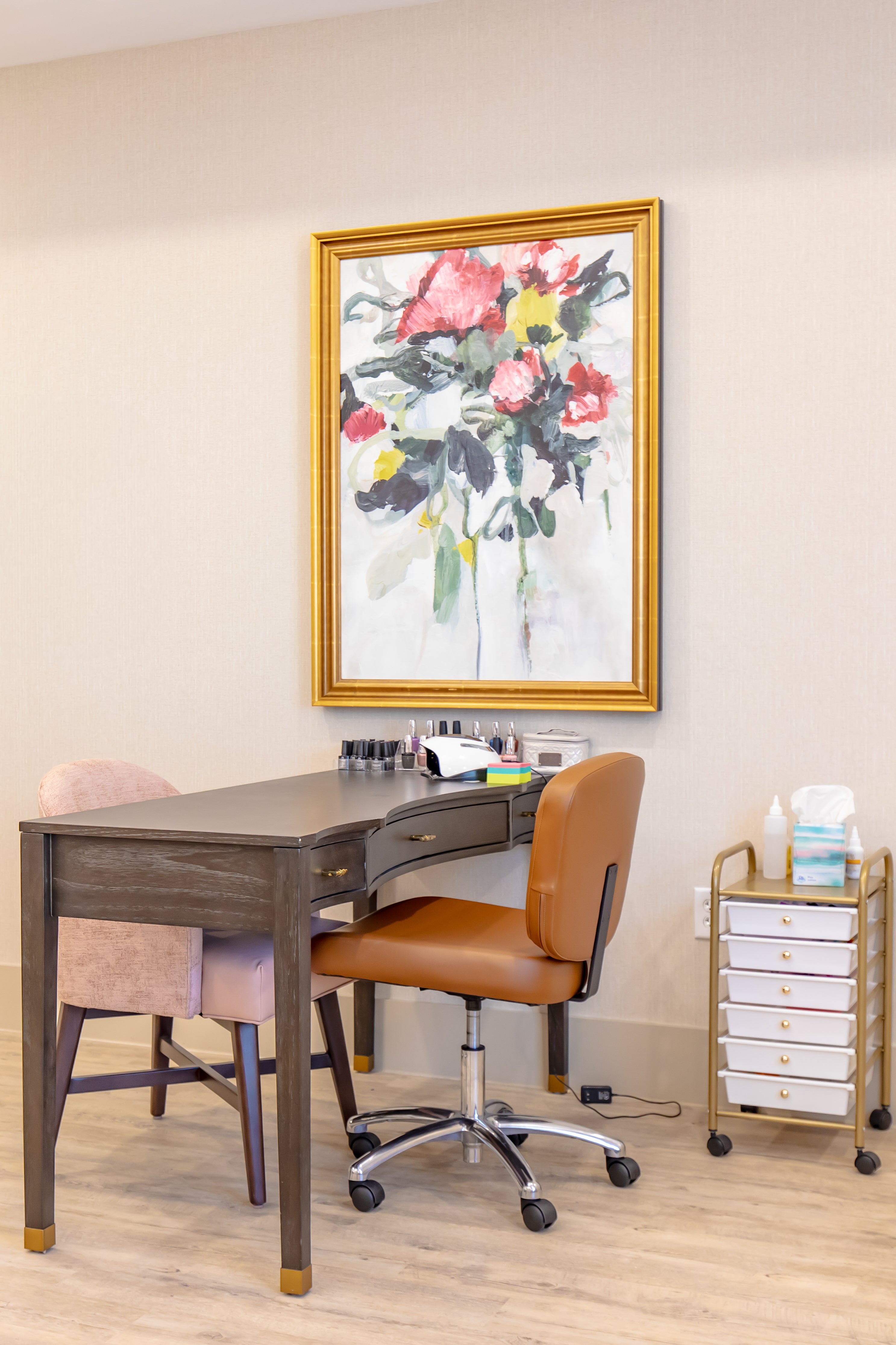 Home office with a desk, chair, and floral painting on the wall.