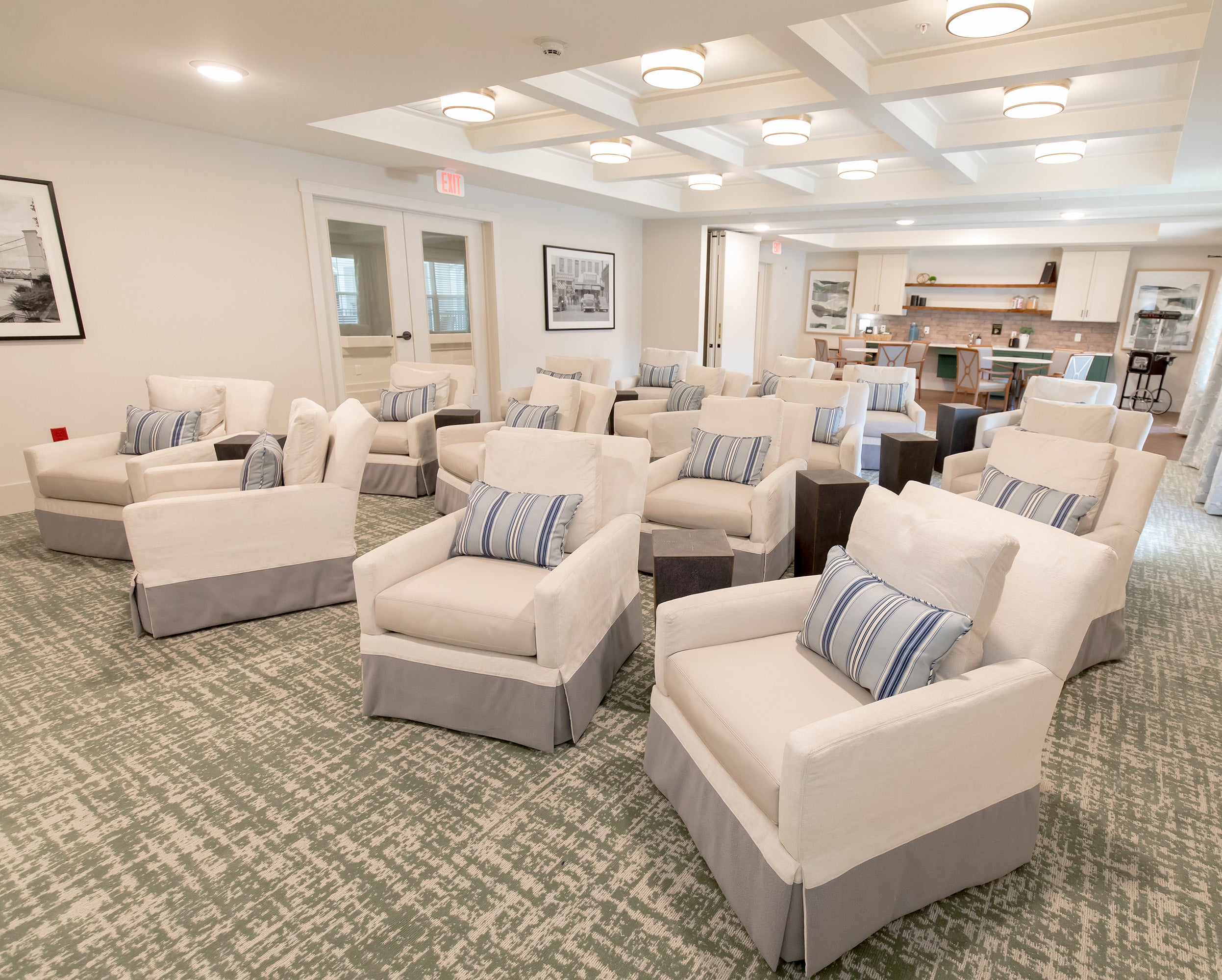 Modern living room with white chairs and gray cushions on a patterned carpet.