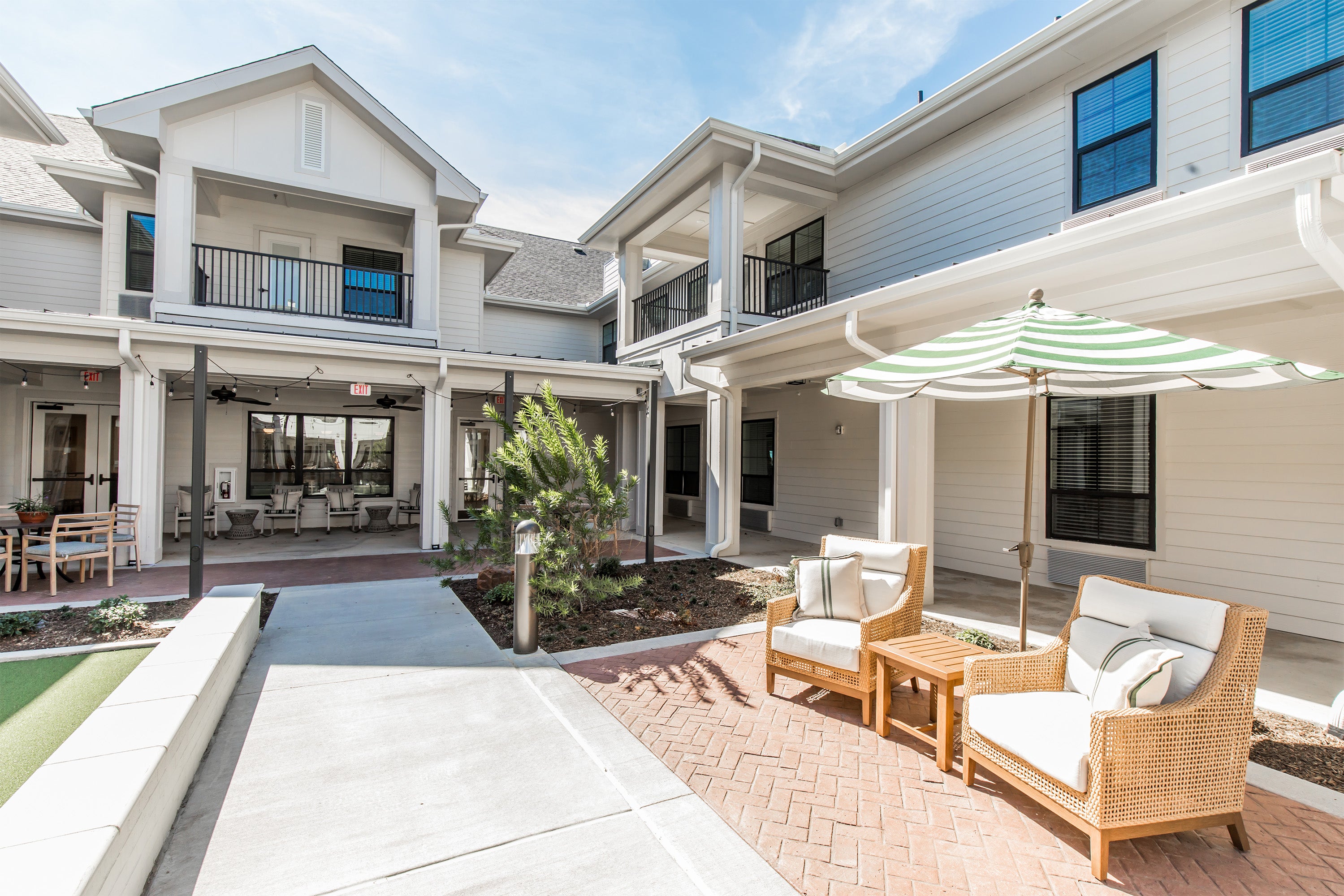 Outdoor patio area with furniture and umbrella in front of a modern house.