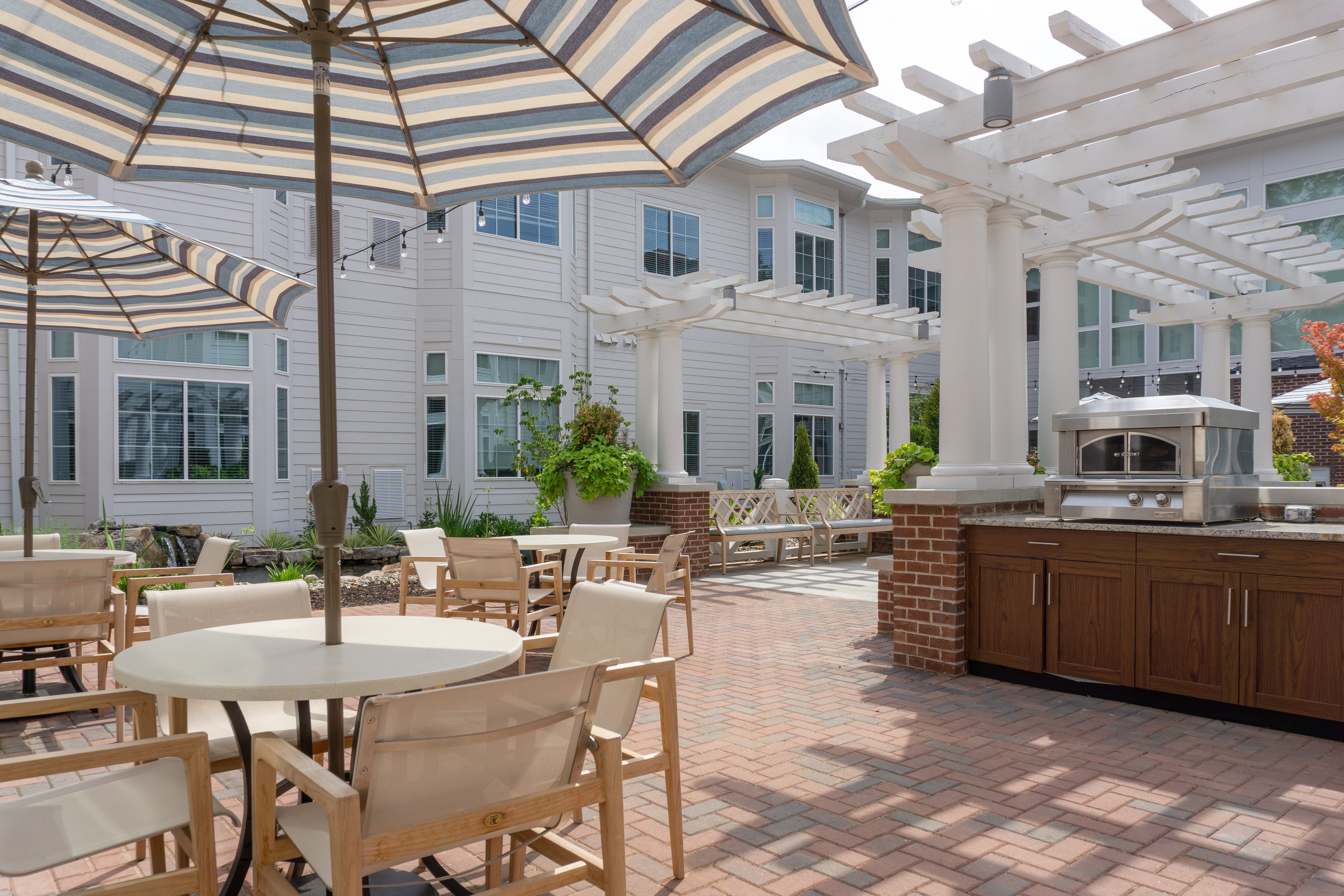 Outdoor patio area with tables, chairs, and umbrellas in front of a building.