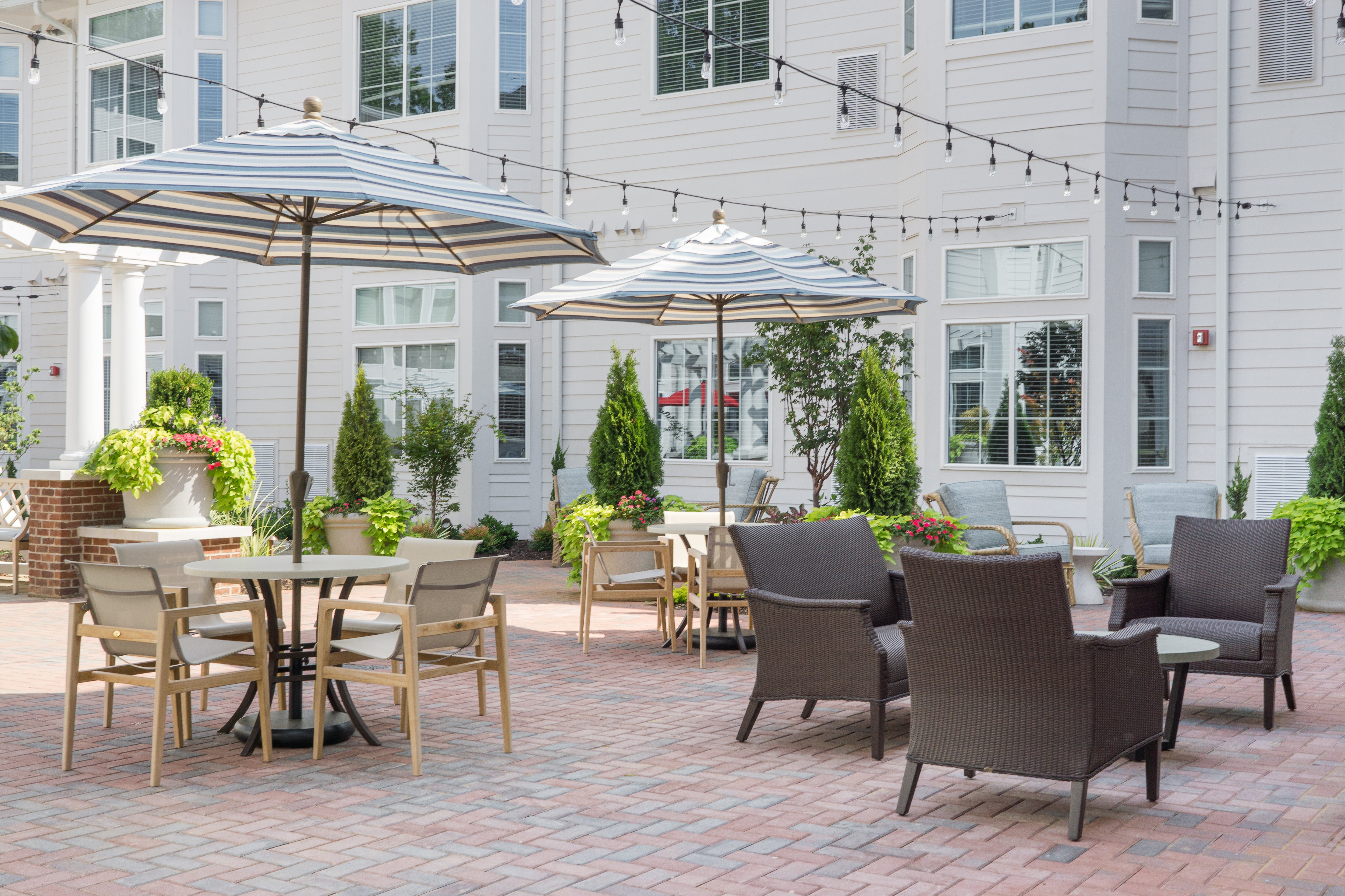 Outdoor patio area with tables, chairs, and umbrellas in front of a building.