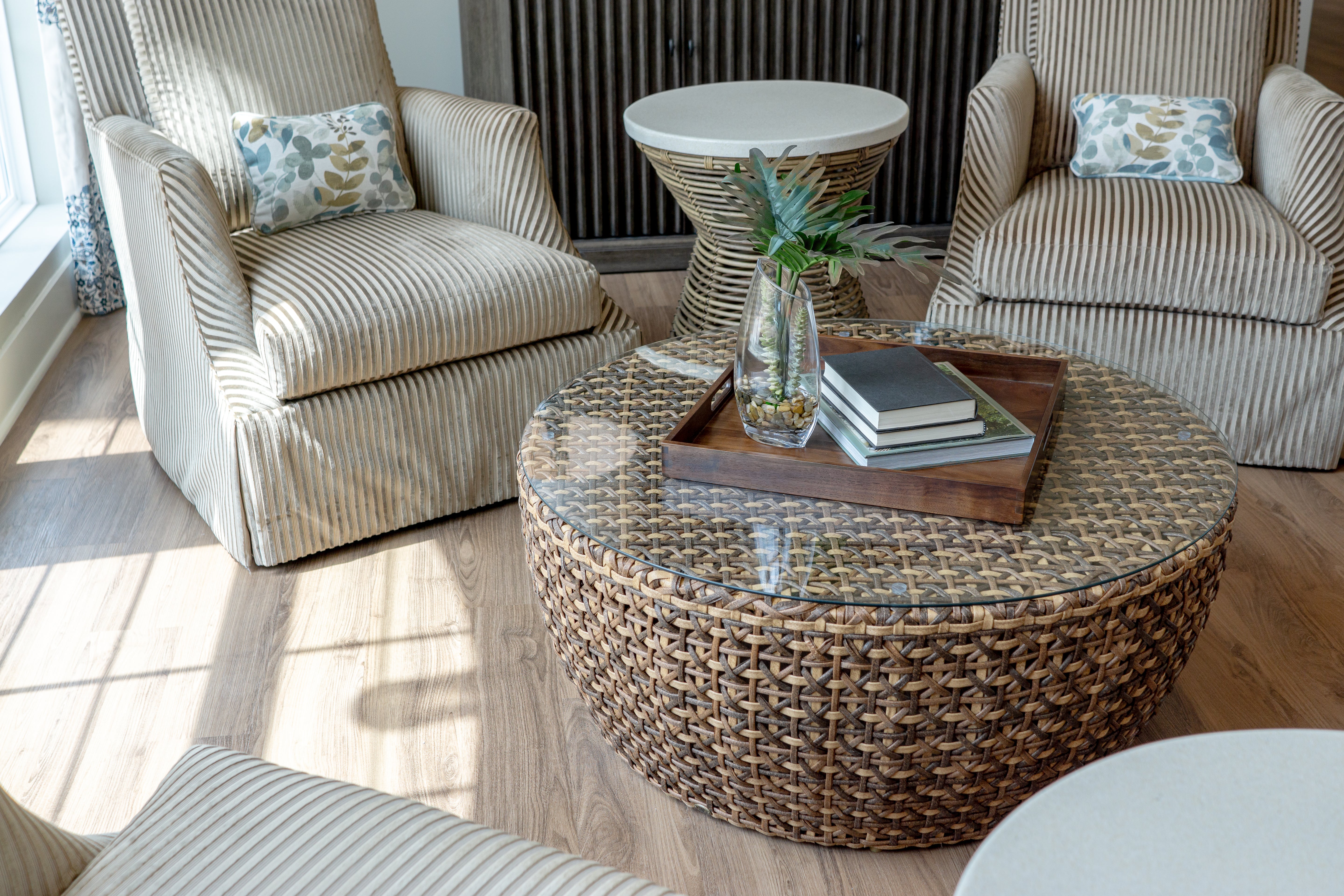 Living room with wicker furniture including upholstered chairs and a woven coffee table.