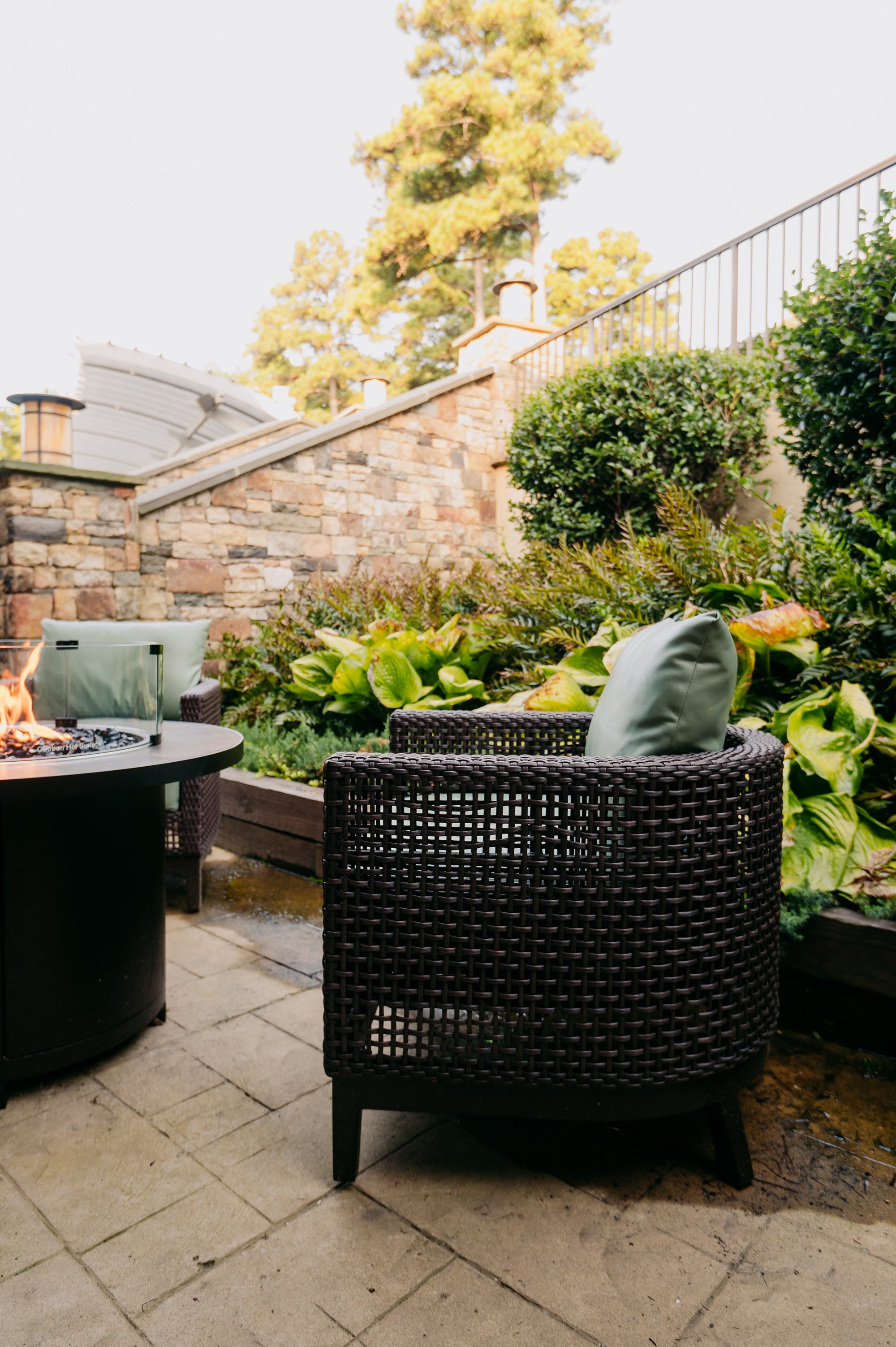 Outdoor patio with wicker chair, fire pit, and greenery