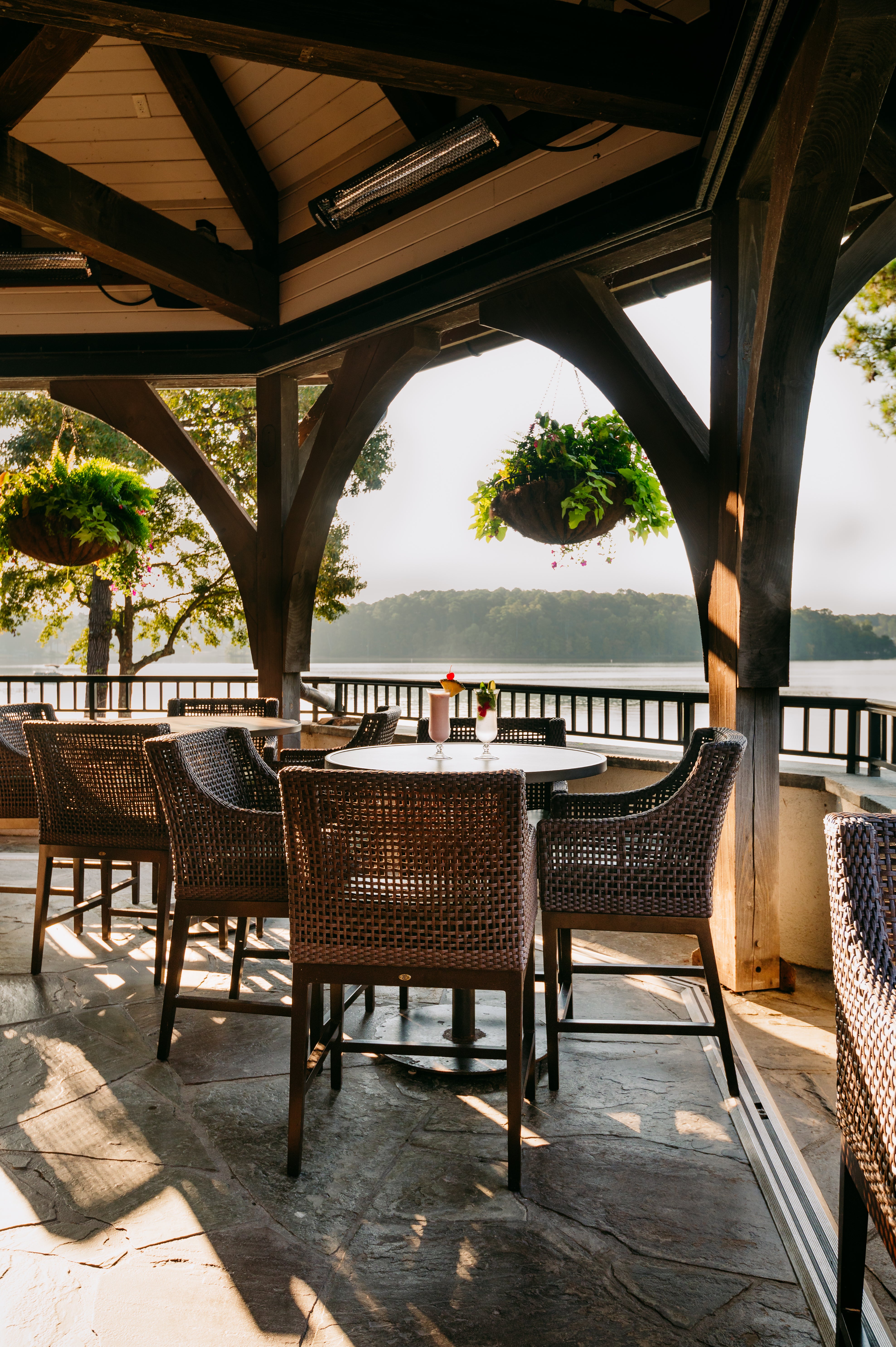 Outdoor patio with wicker chairs and tables overlooking a lake.