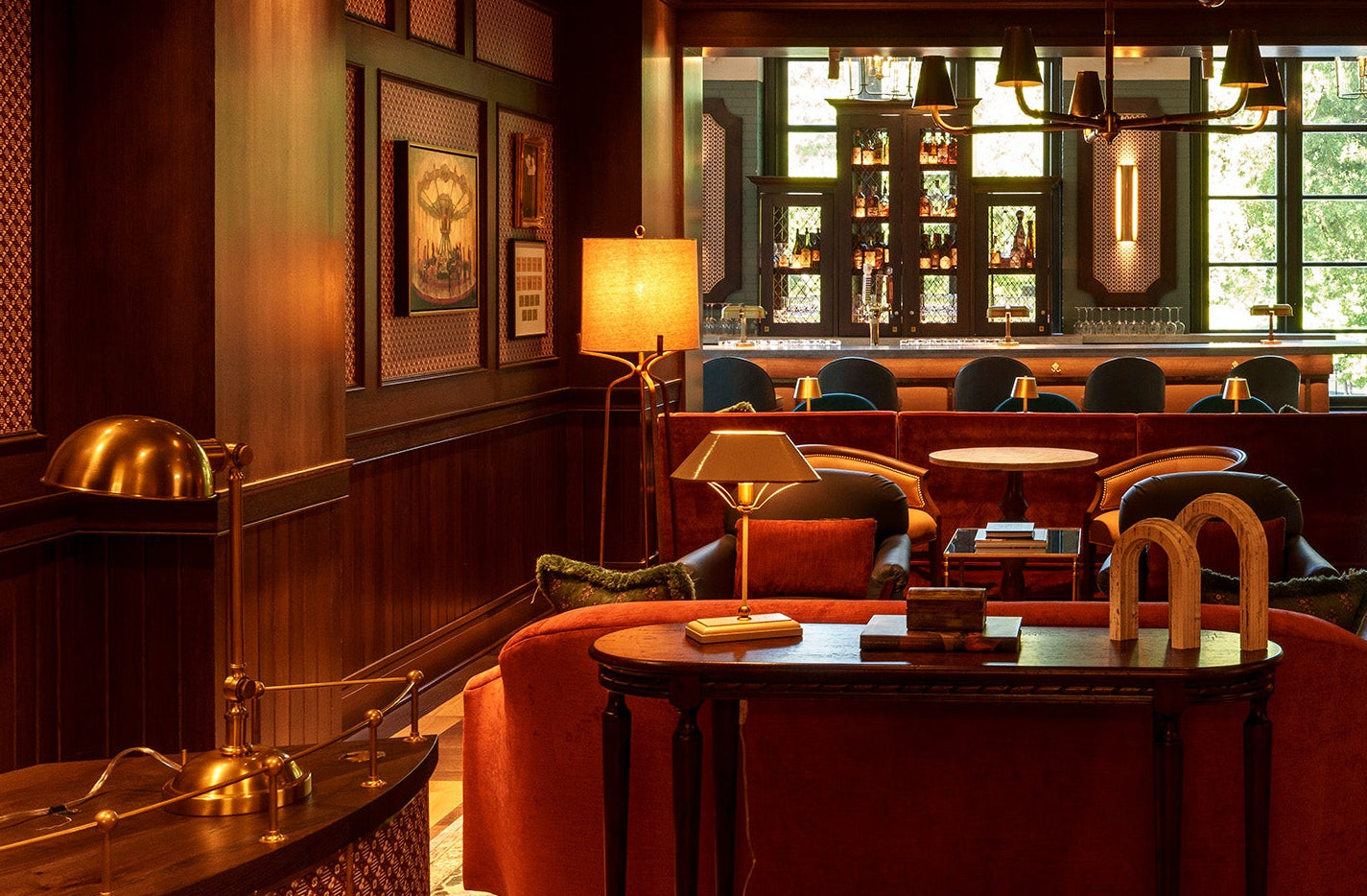 Cozy bar interior with red chairs, wooden tables, and framed pictures on the wall.
