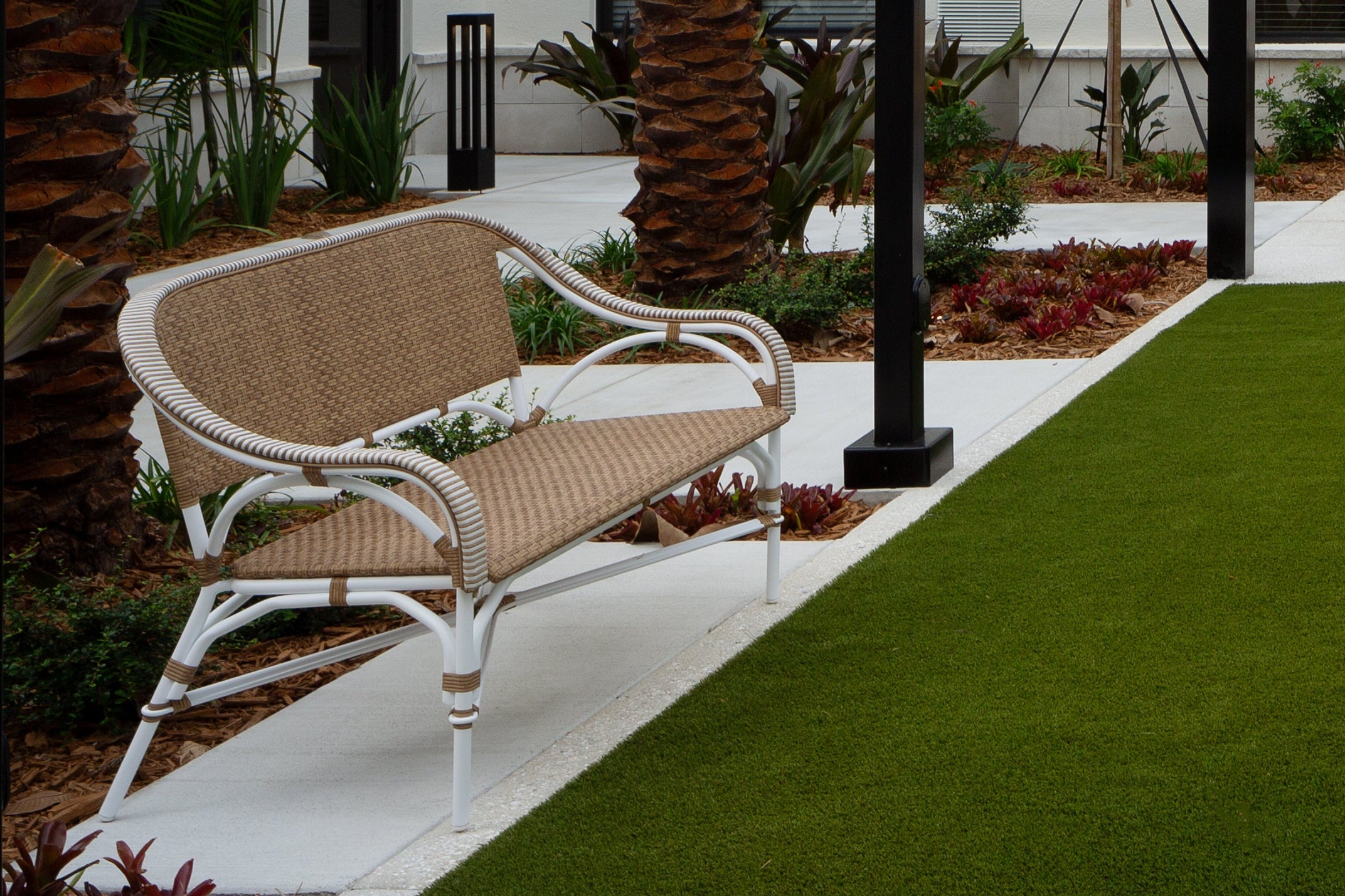 Outdoor patio area with a pergola, chairs, and palm trees.