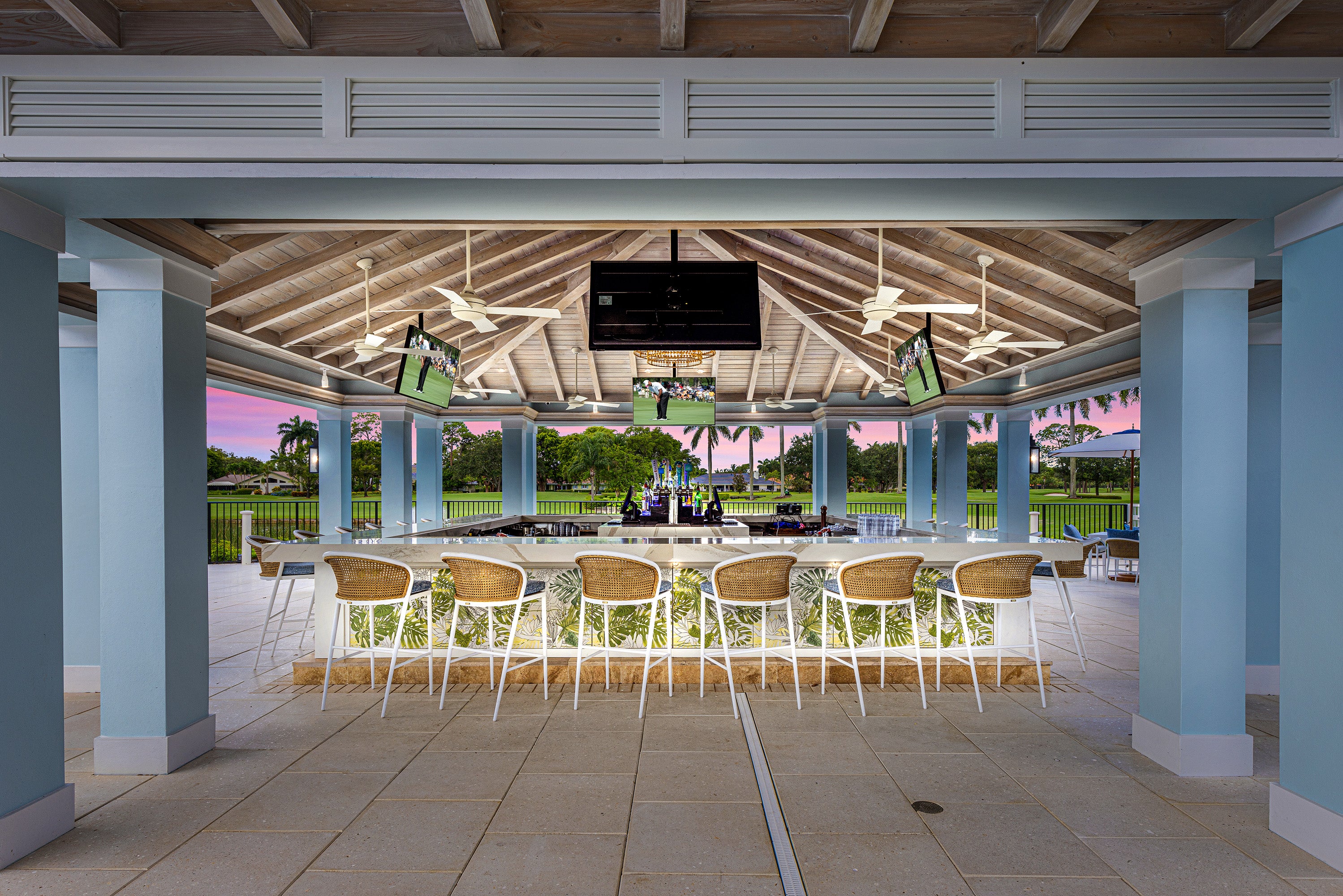 Outdoor patio area with a bar and chairs, featuring a television screen.