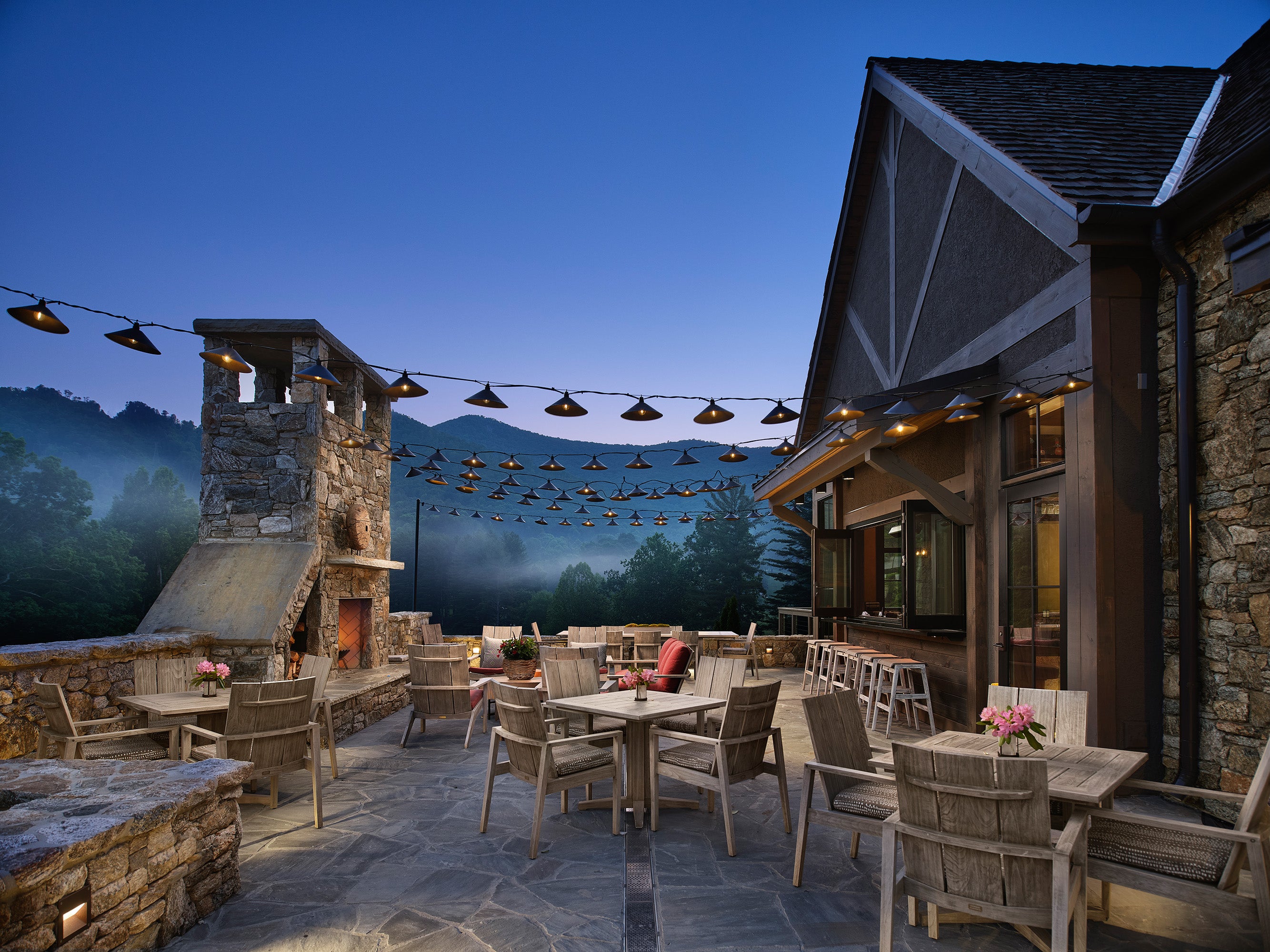 Outdoor patio area with tables and chairs near a building with mountain views.