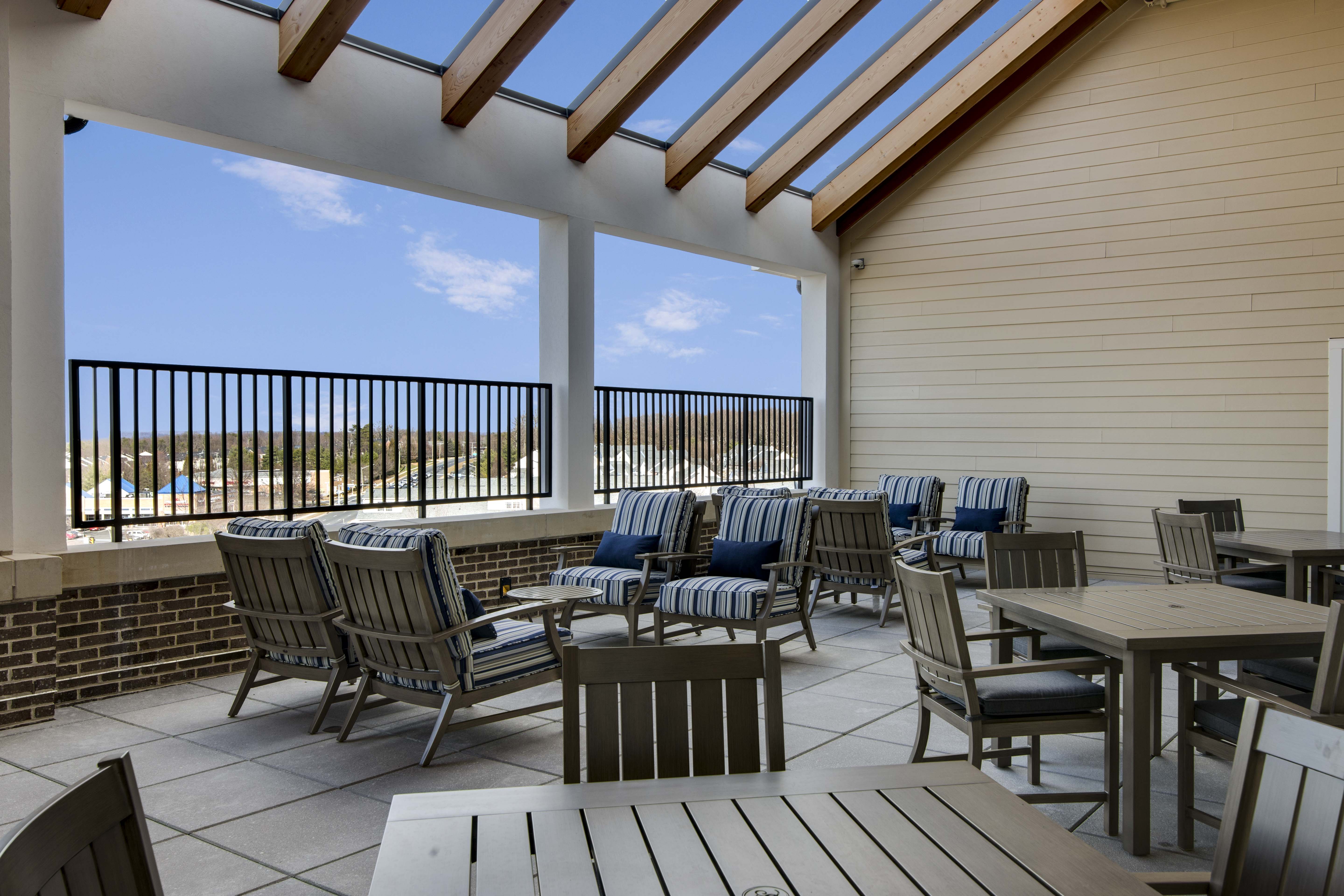 Outdoor patio area with tables and chairs on a deck overlooking a scenic view.