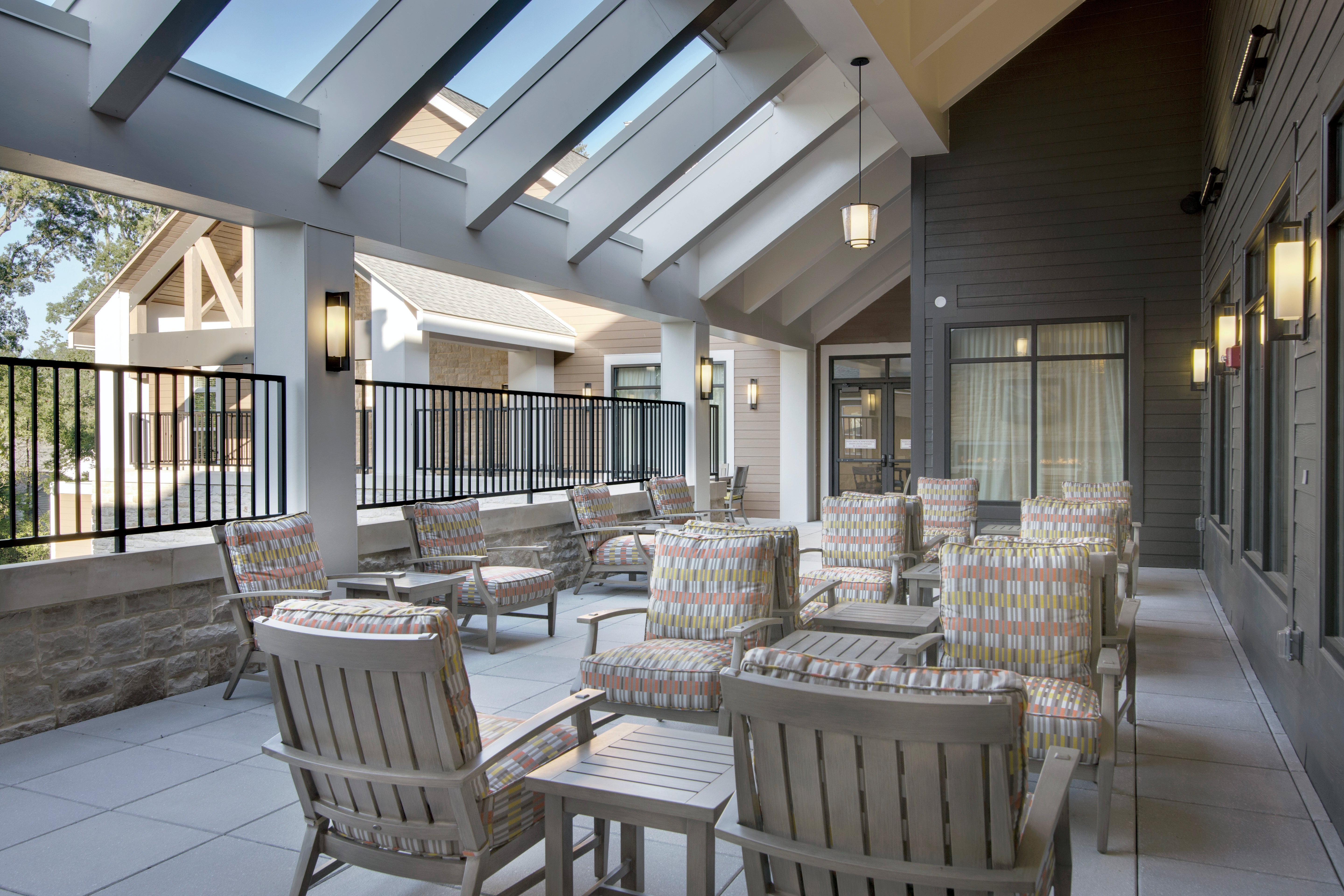 Outdoor patio area with chairs and tables under a modern roof design.